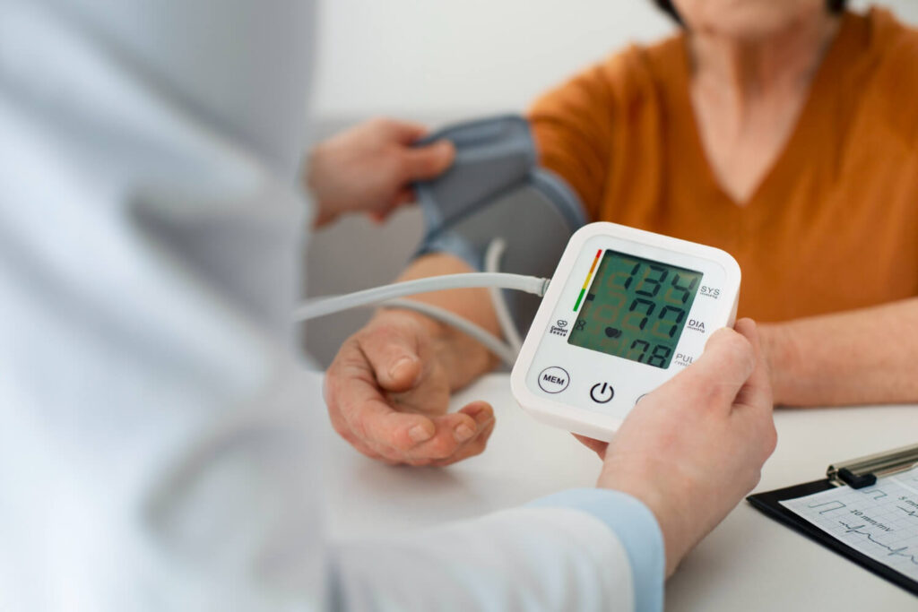 Medição da pressão arterial com aparelho digital em paciente durante consulta médica, indicando valores elevados e reforçando cuidados sobre pressão alta e o que fazer para controlar a hipertensão.